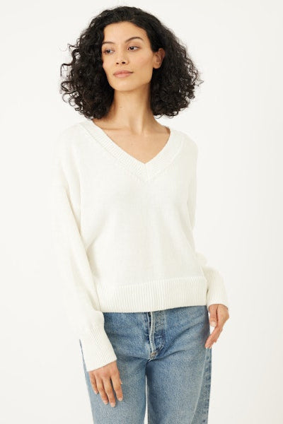 Woman wearing a white sweater and blue jeans on a white background