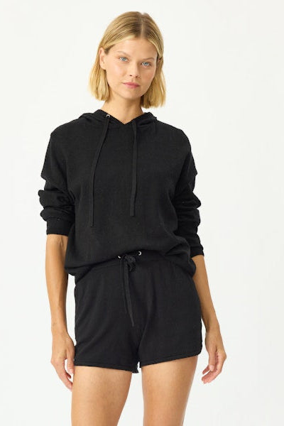 Woman wearing a black hoodie and shorts set on a white background