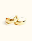 A pair of gold-plated brass hoop earrings with a shiny finish, displayed against a white background.