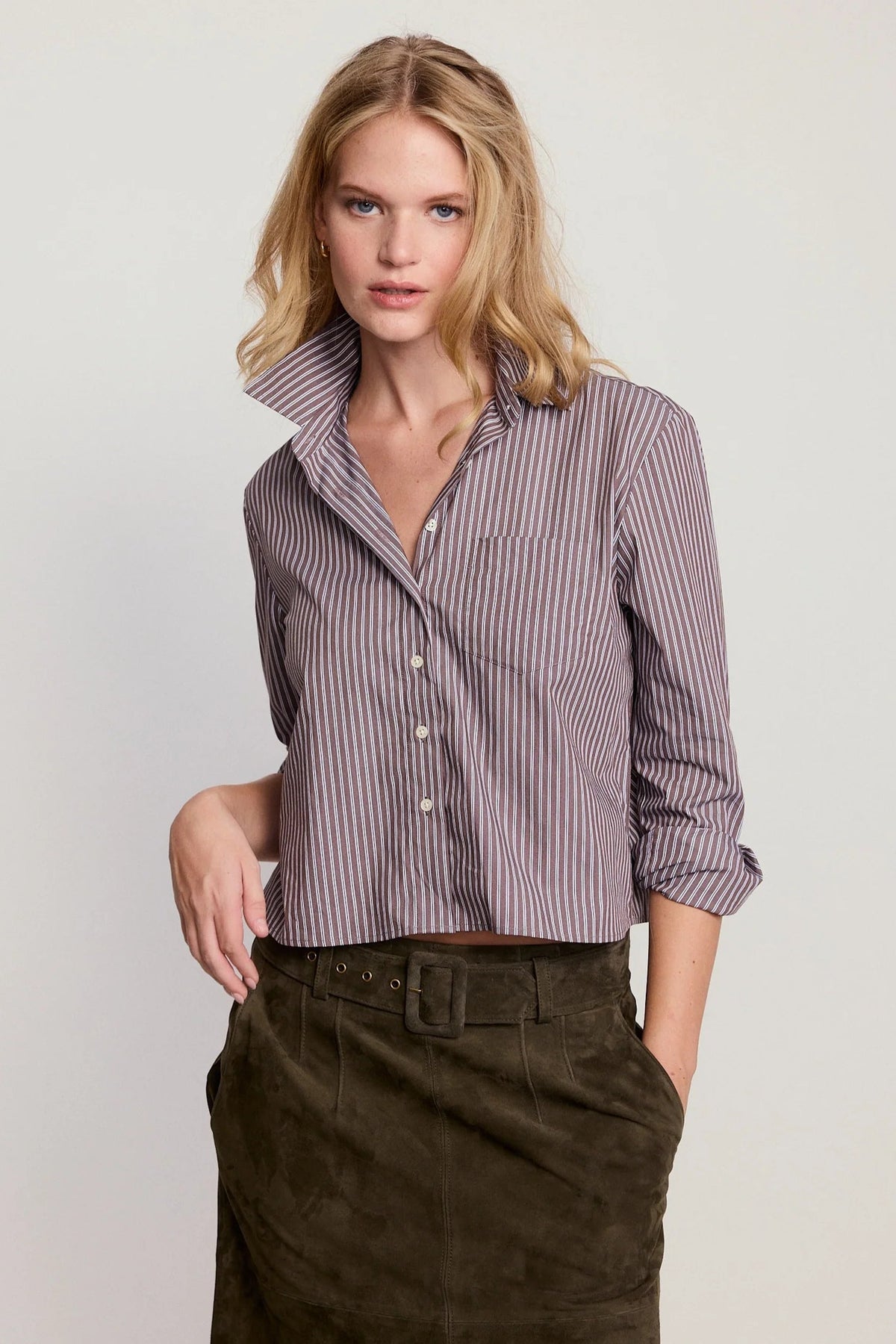 Woman wearing a striped shirt and dark pants on a plain background