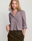 Woman wearing a striped shirt and dark pants on a plain background