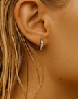 Close-up of an ear with a silver hoop earring on a blurred background