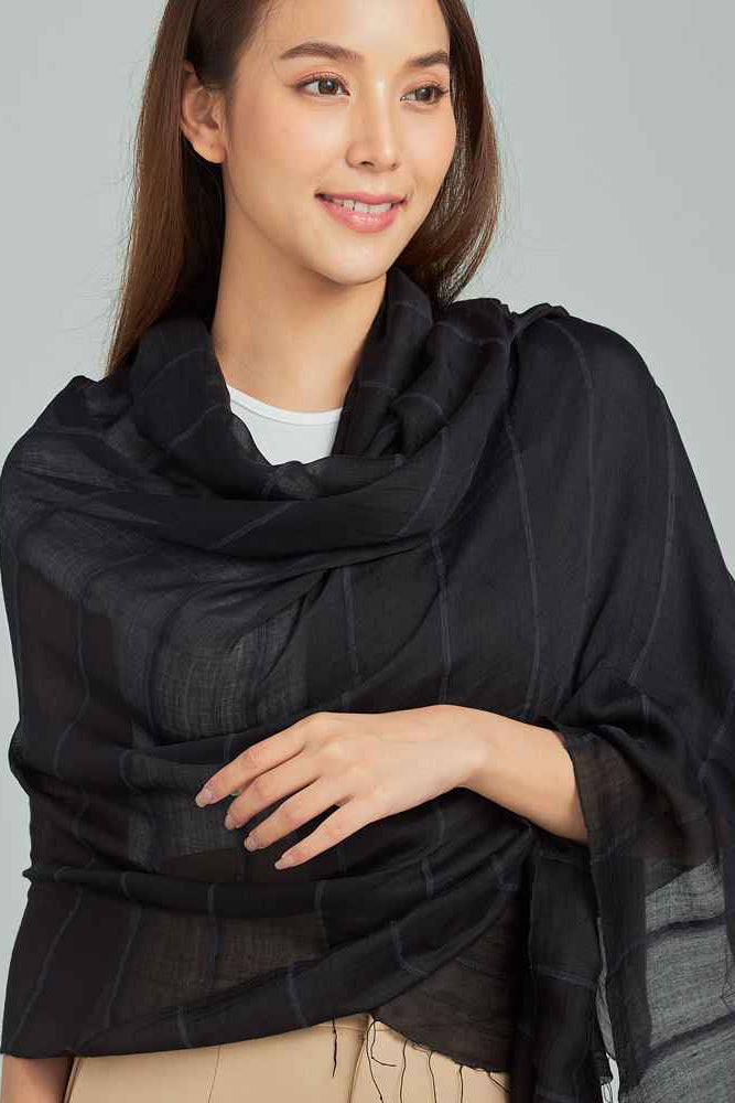 Woman wearing a black scarf on a gray background