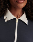 Close-up of a person wearing a navy blue top with a white collar and zipper detail.