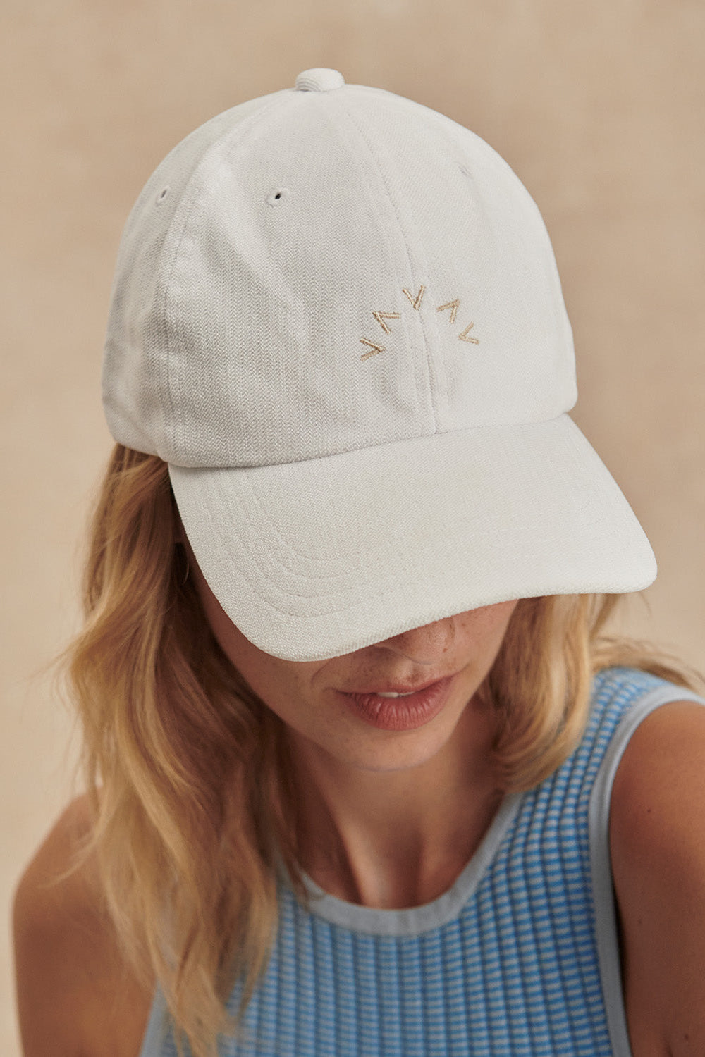 Person wearing a light gray cap with 'WAVY' branding on a beige background