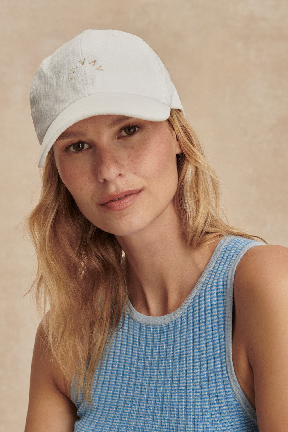 Woman wearing a white cap with a beige background