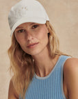 Woman wearing a white cap with a beige background