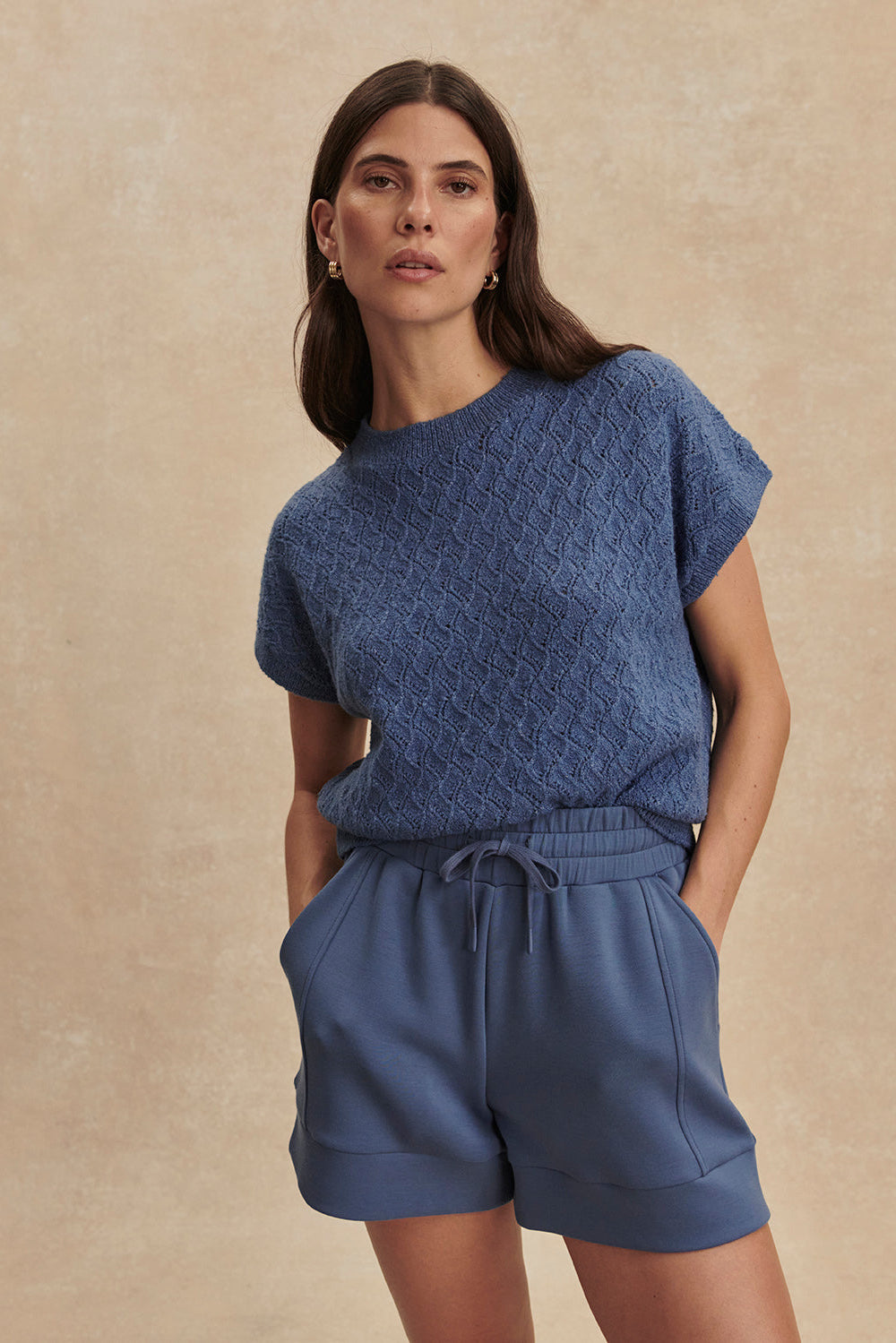 Woman wearing a blue outfit against a beige background