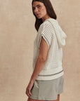 Woman wearing a white crochet top and light green shorts against a beige background
