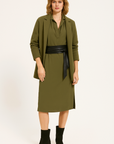 Woman wearing a green dress with a black belt on a white background
