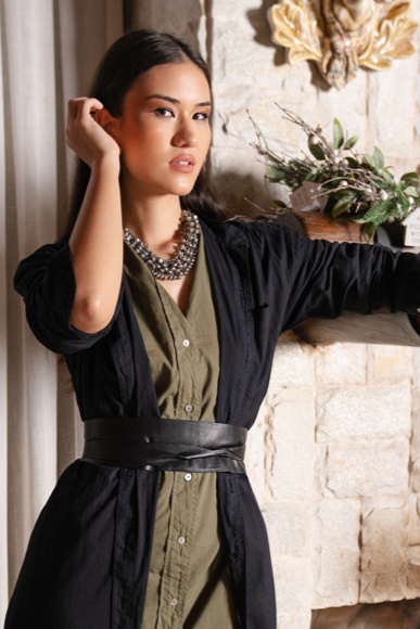 Woman in a black and green dress standing in a room with decorative elements.