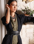 Woman in a black and green dress standing in a room with decorative elements.