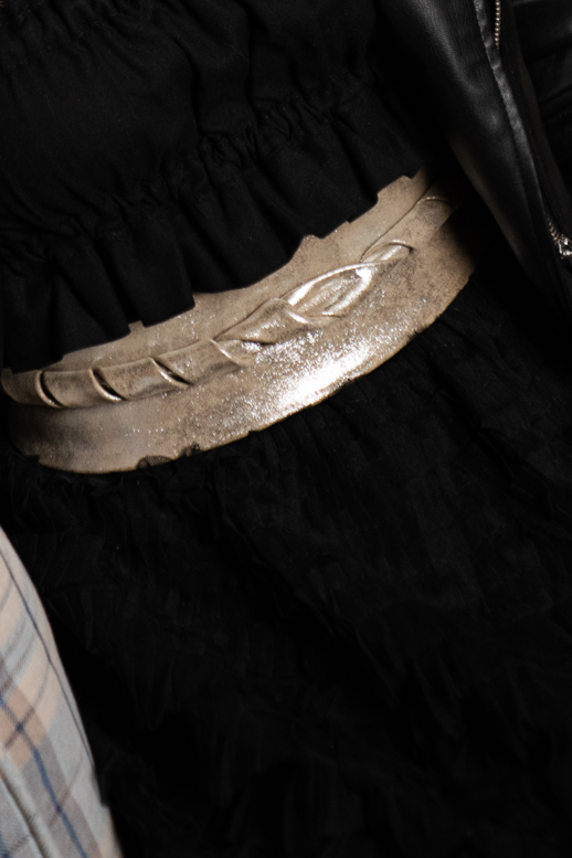 Person wearing a black outfit with a metallic belt