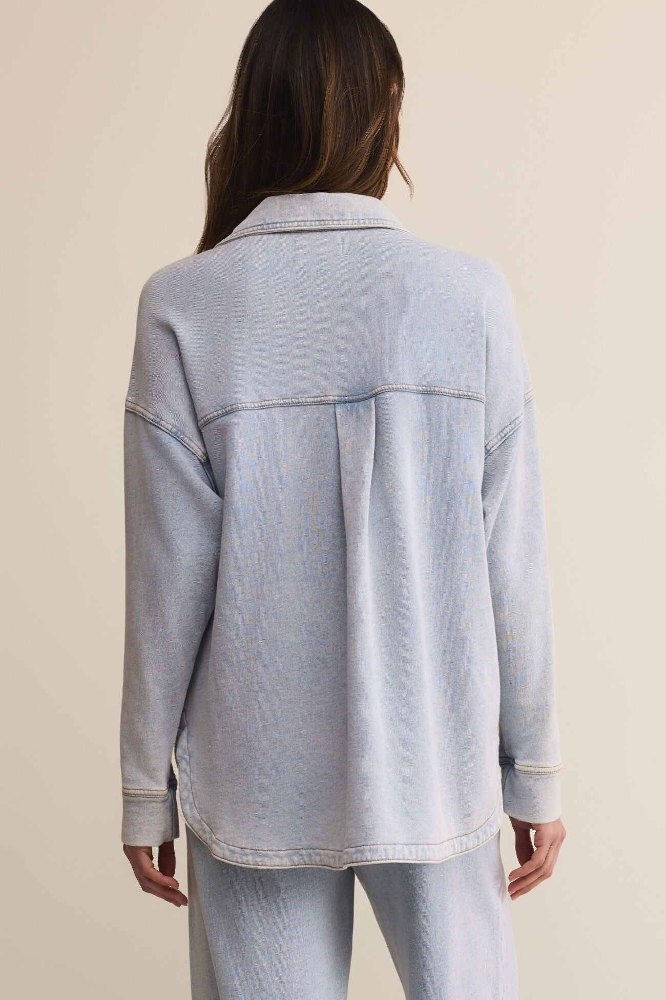 Light blue denim jacket worn by a person on a beige background