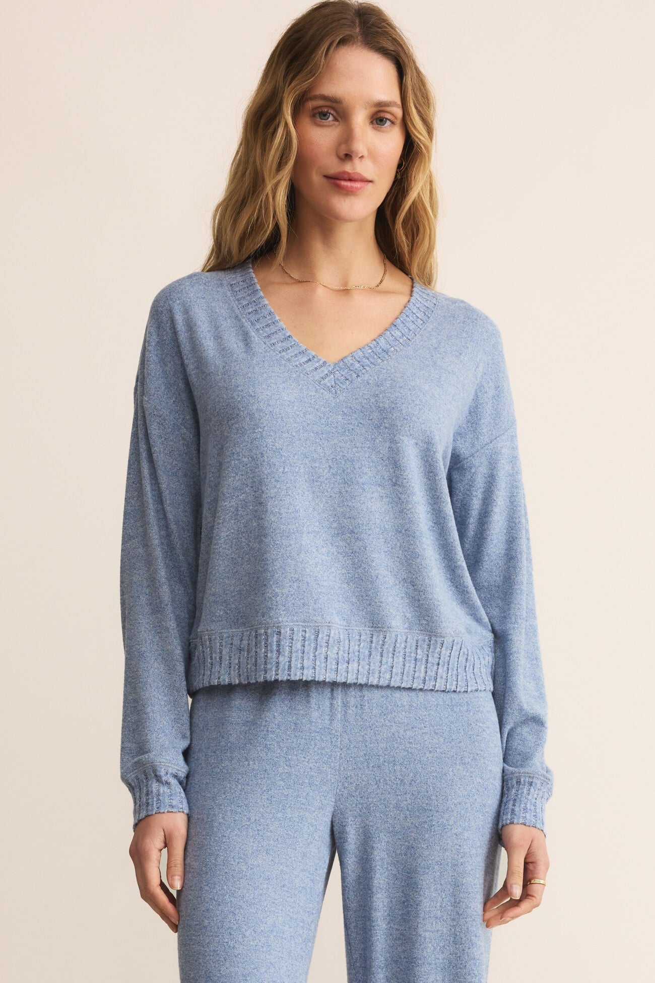 Woman wearing a blue sweater and pants on a beige background