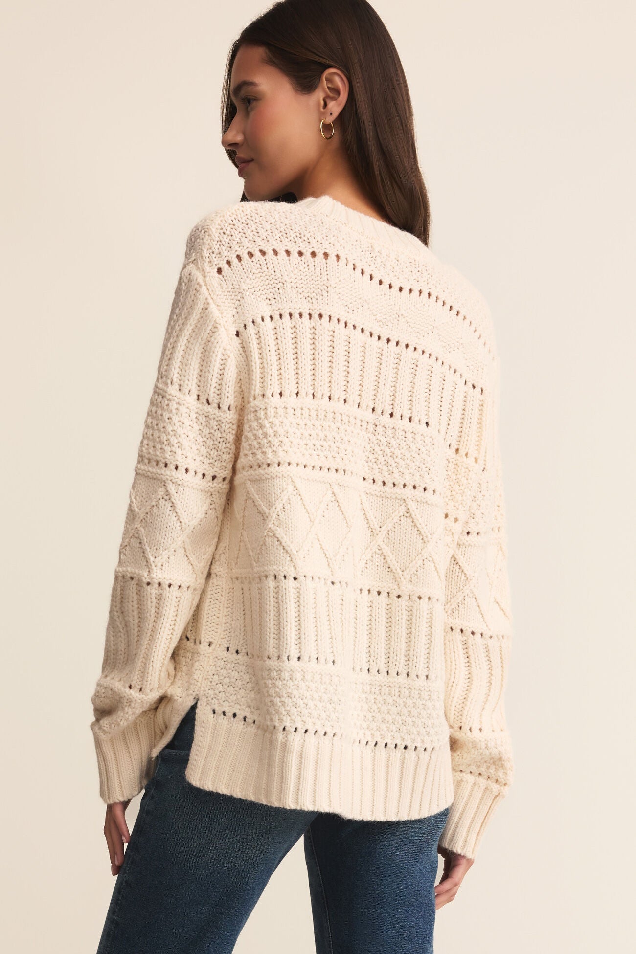 Woman wearing a cream-colored knitted sweater on a beige background