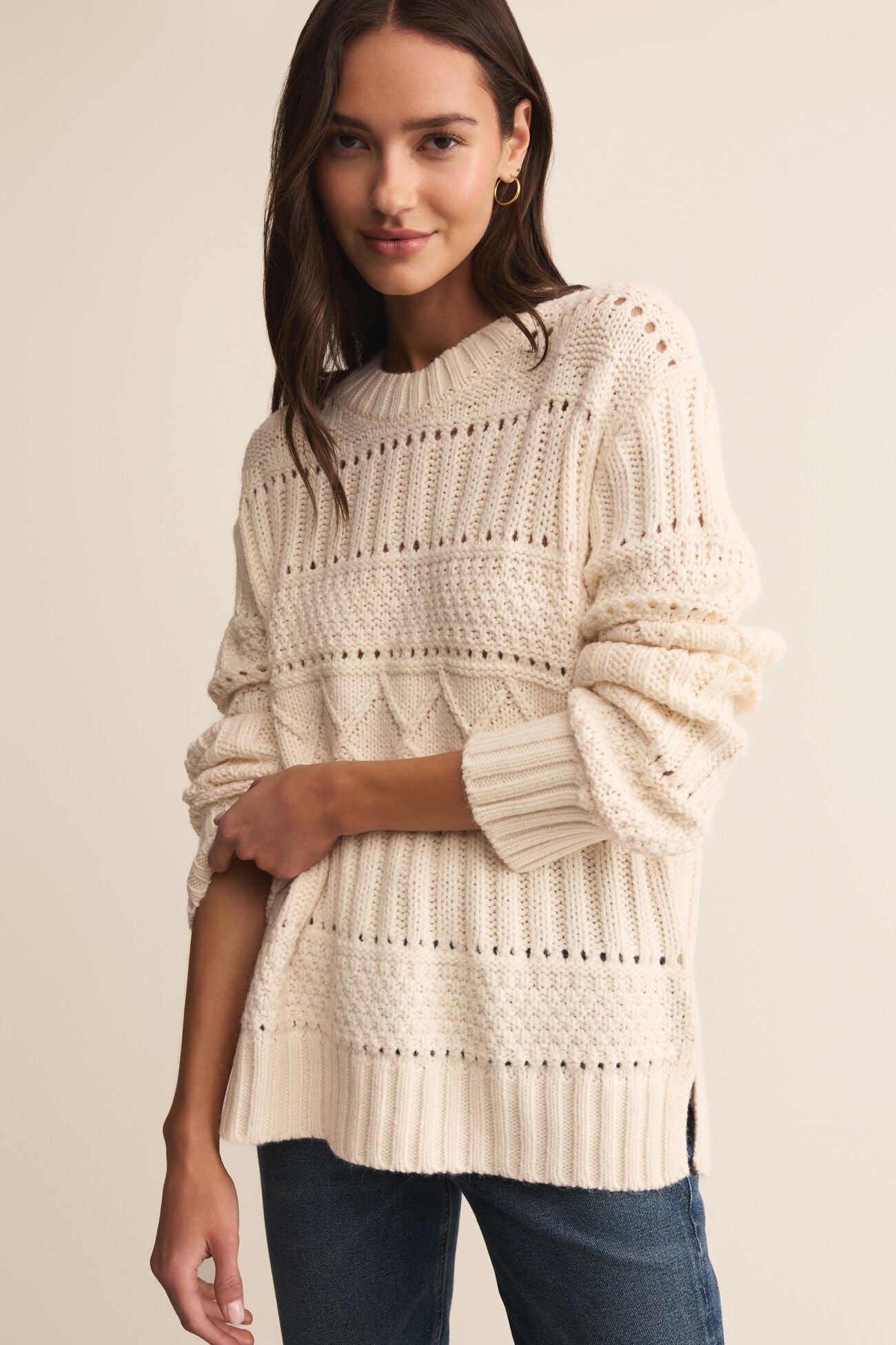 Woman wearing a cream knitted sweater against a beige background