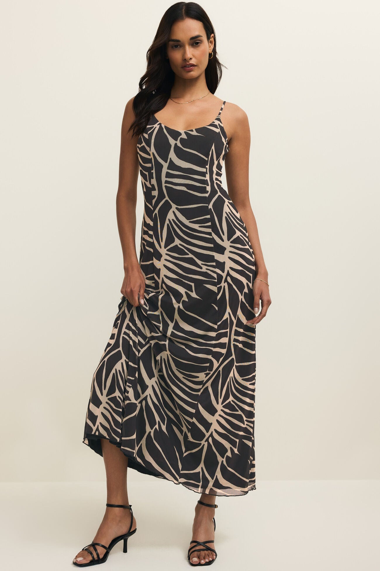 Woman wearing a black and beige patterned dress on a white background