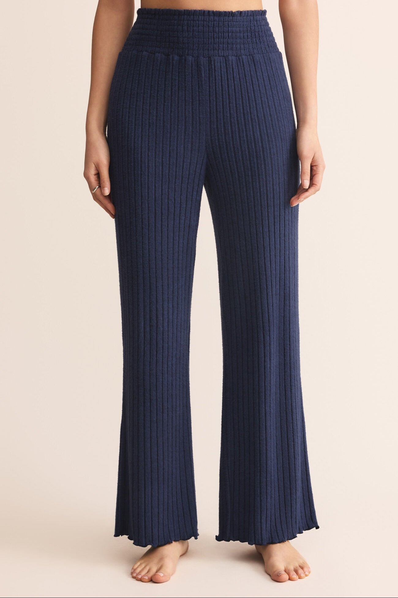 Navy ribbed pants worn by a person on a beige background