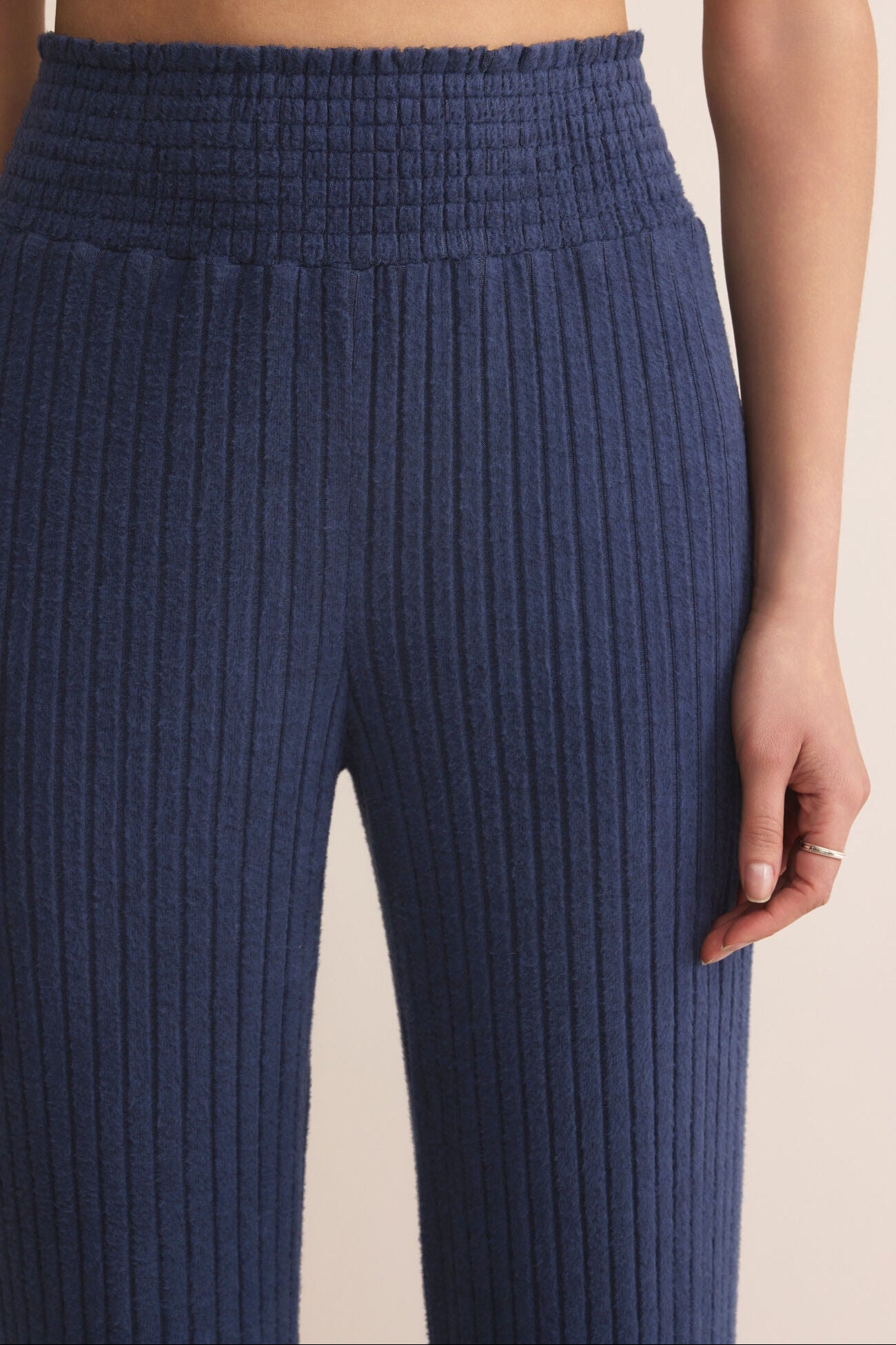 Navy ribbed pants worn by a person on a beige background