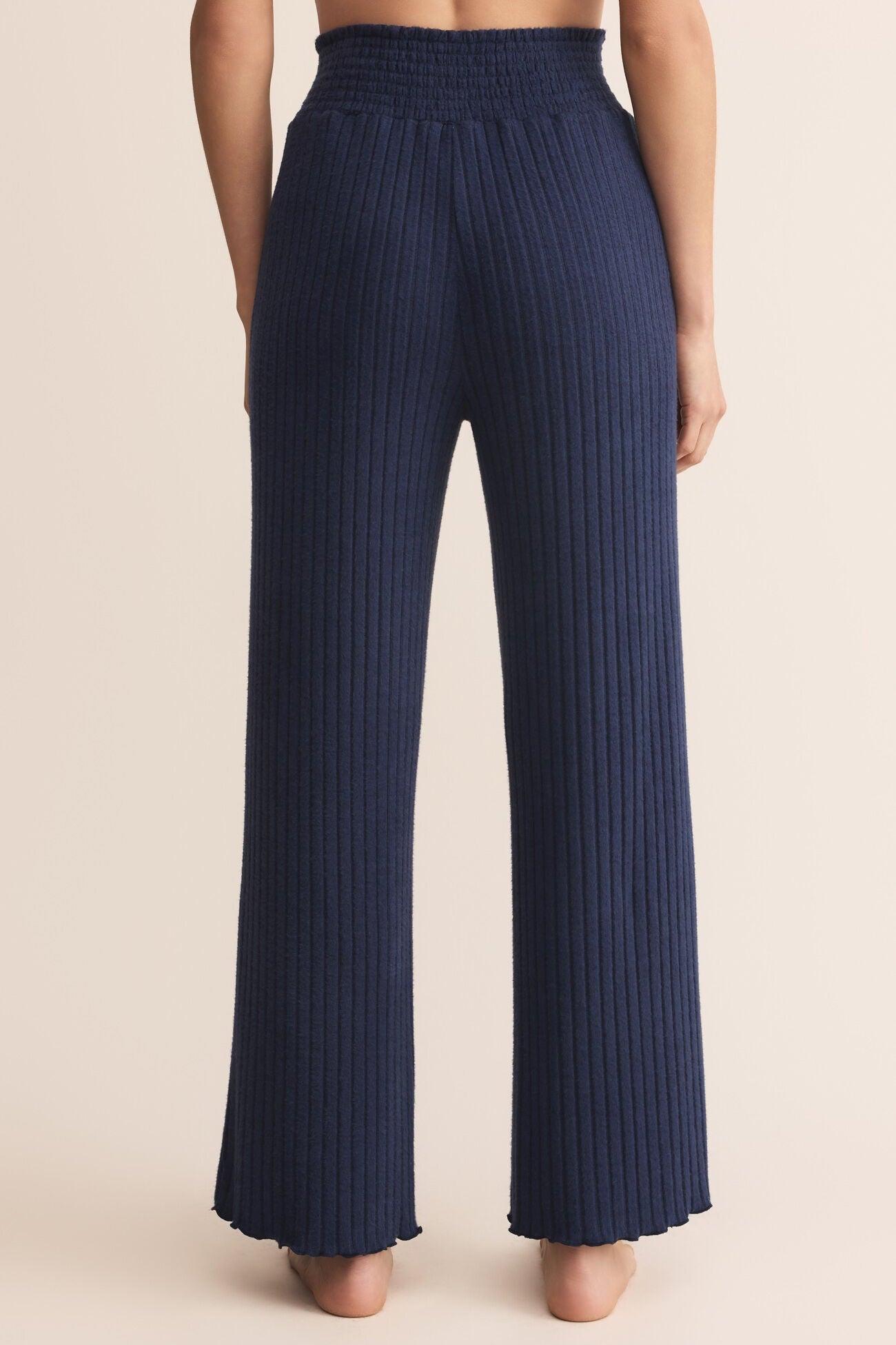 Navy pleated pants worn by a person on a beige background