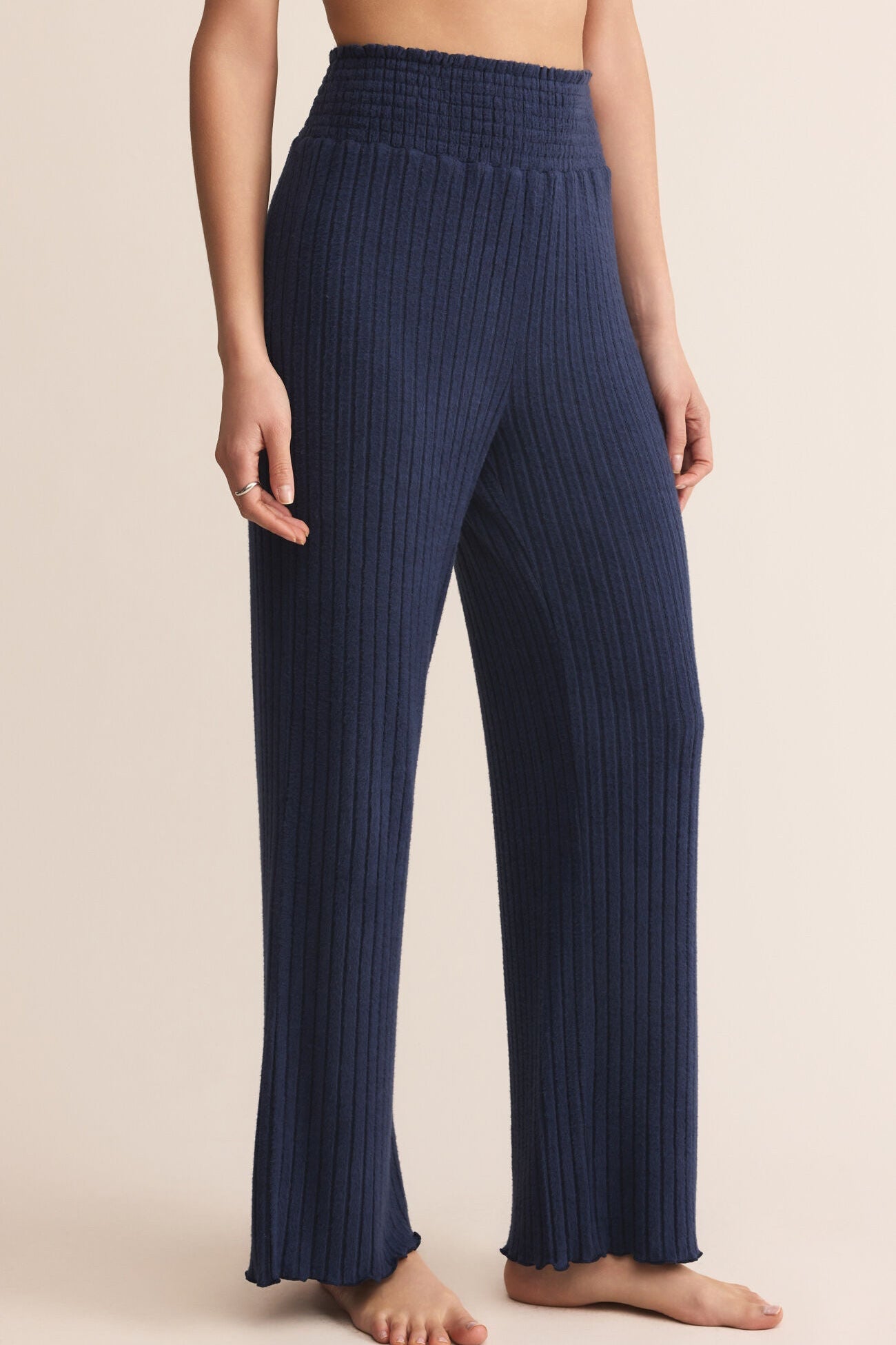 Navy ribbed pants worn by a person on a beige background