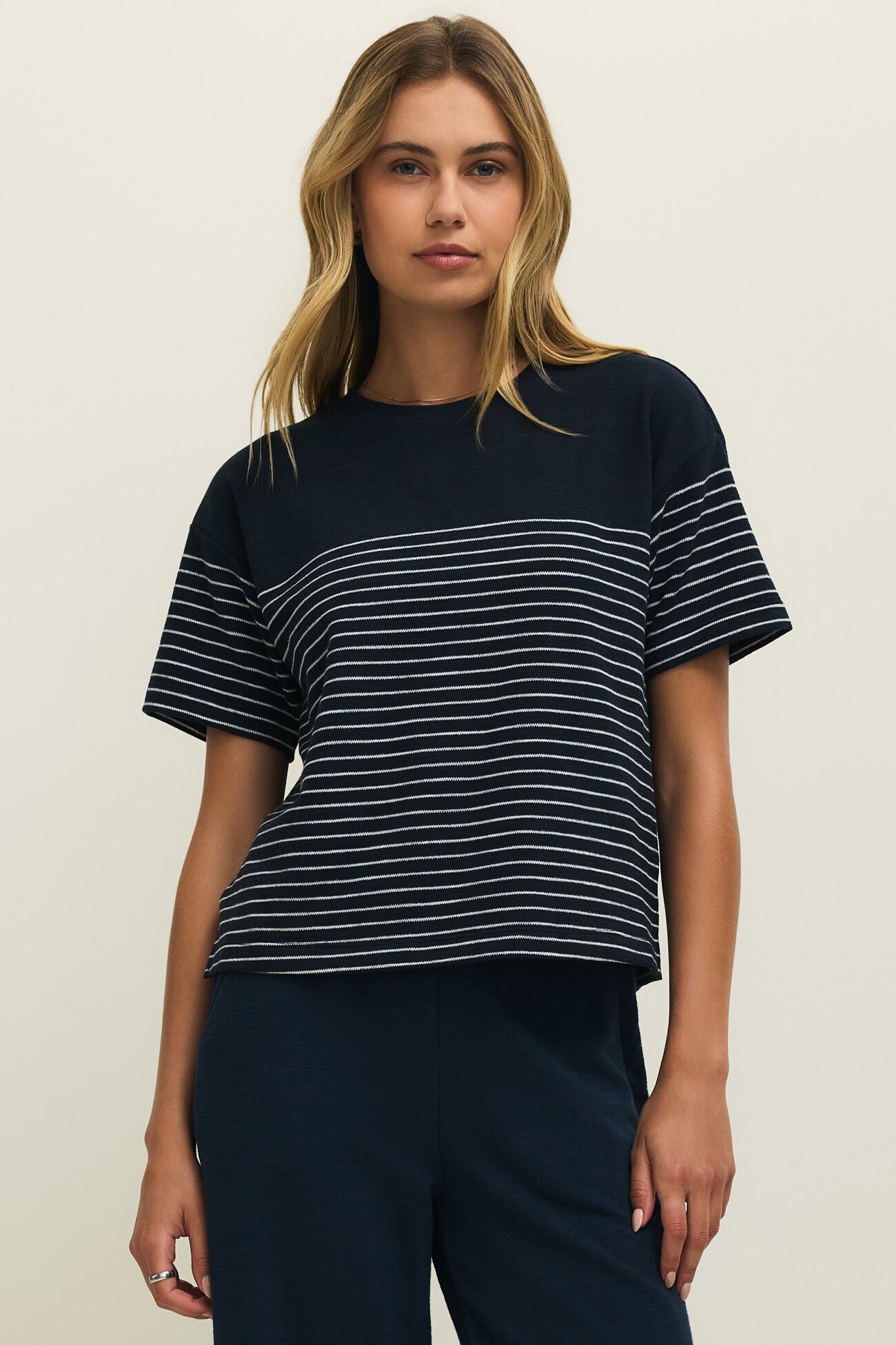 Woman wearing a navy blue and white striped shirt against a plain background