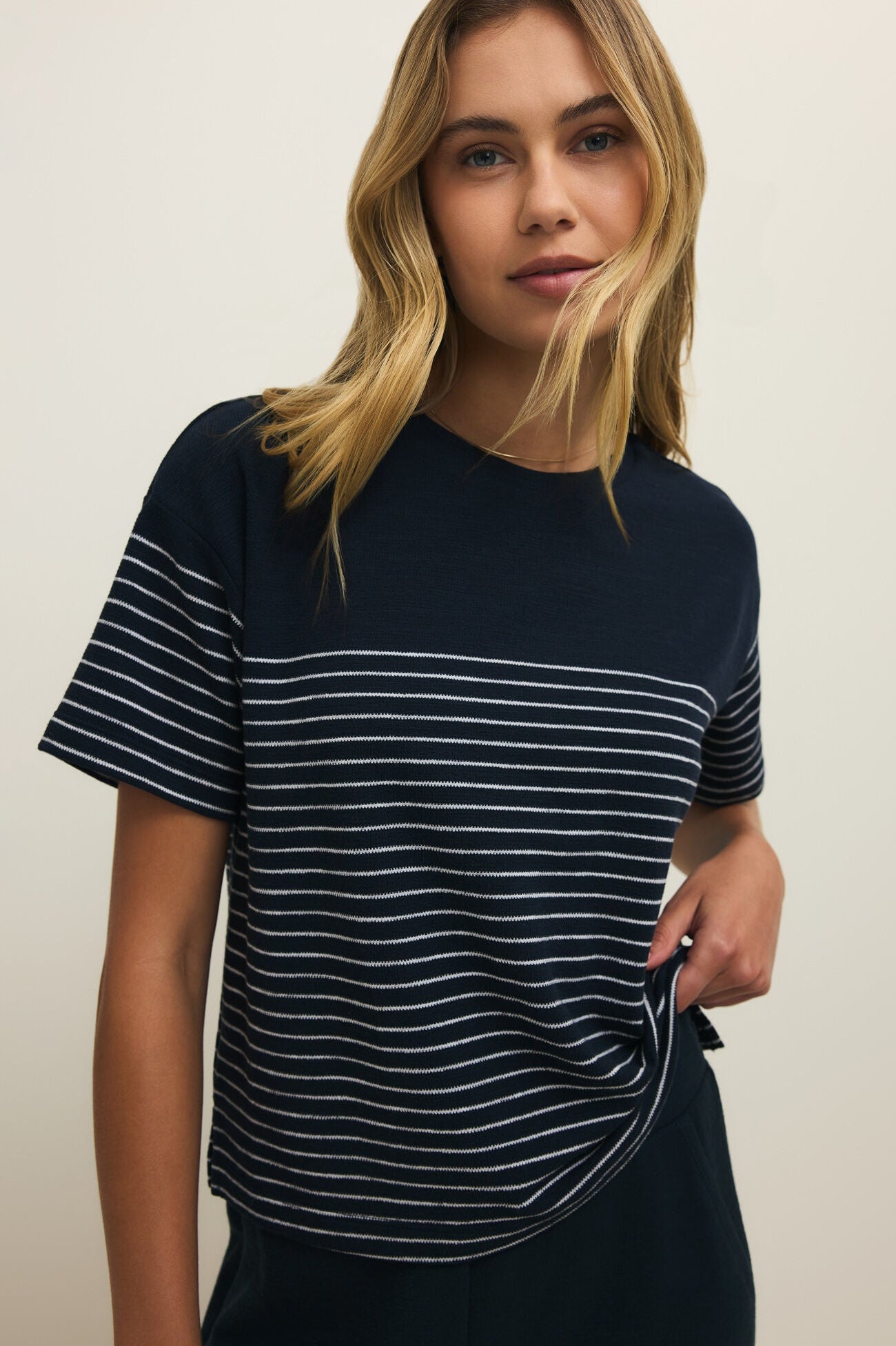 Woman wearing a navy blue and white striped t-shirt against a plain background