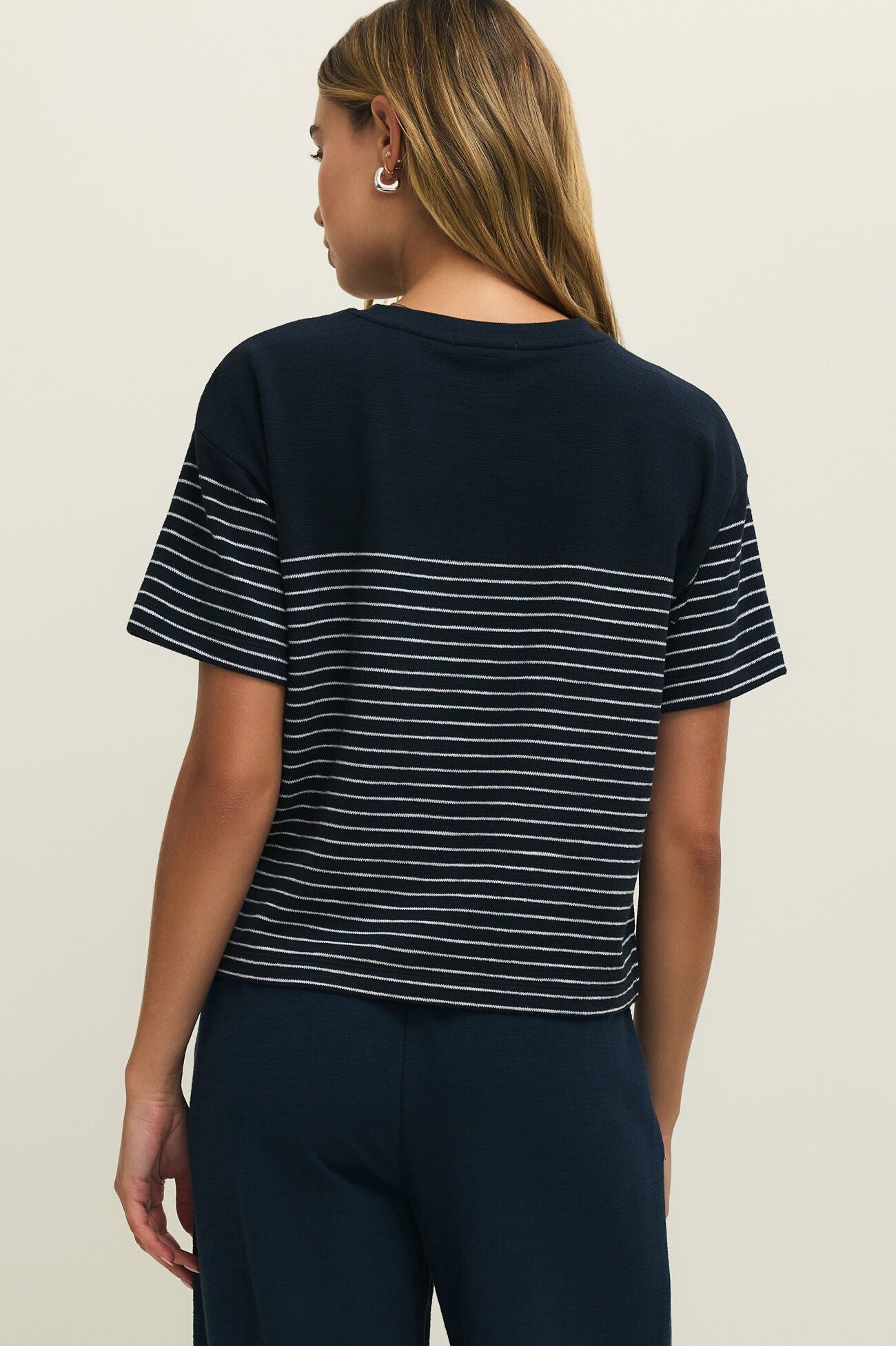 Woman wearing a navy blue t-shirt with white stripes on a plain background