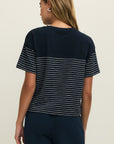 Woman wearing a navy blue t-shirt with white stripes on a plain background