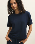 Woman wearing a navy blue t-shirt and pants against a beige background