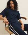Woman wearing a navy blue outfit with white stripes sitting on a chair.