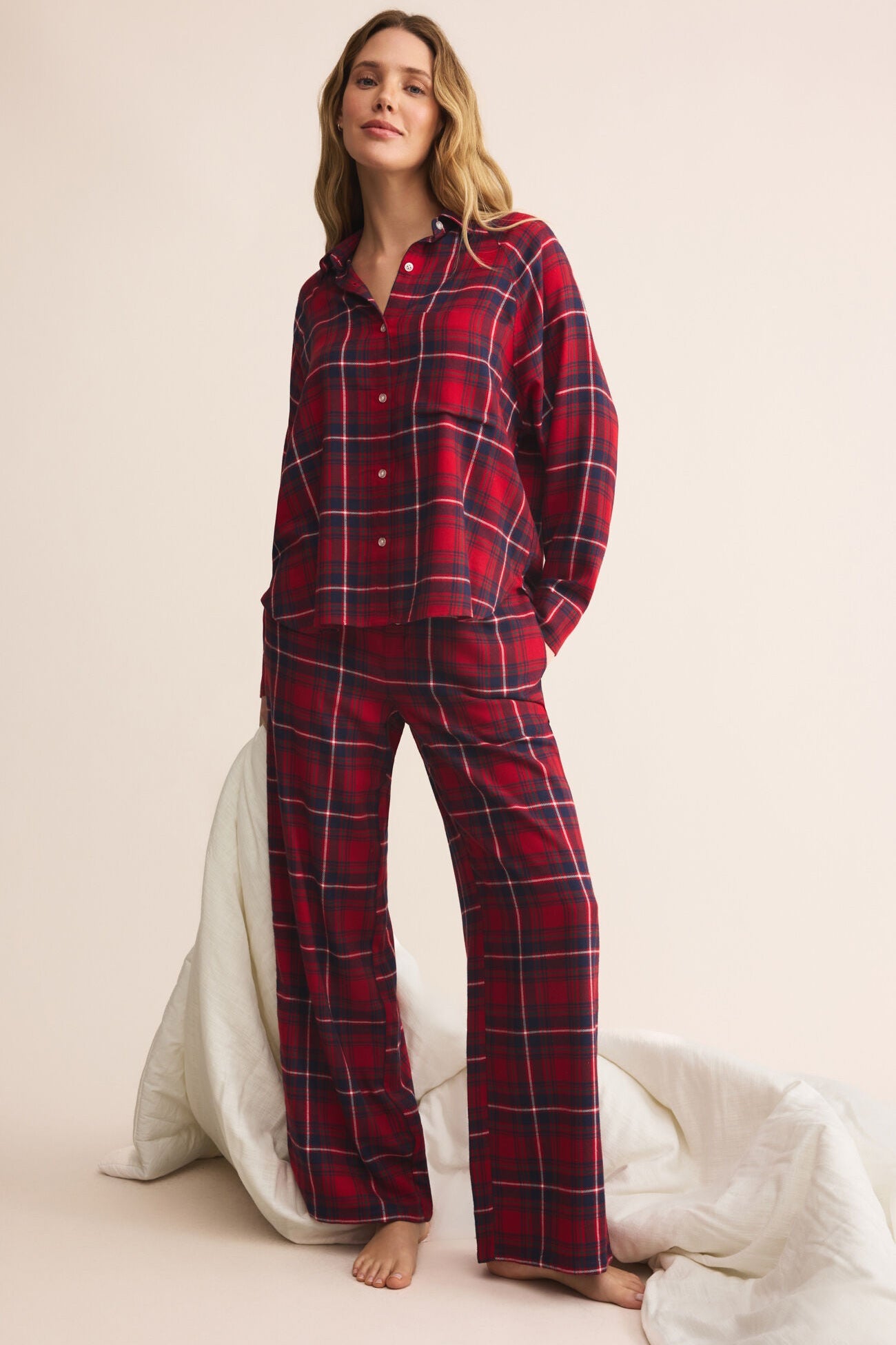 Woman wearing red plaid pajamas on a beige background