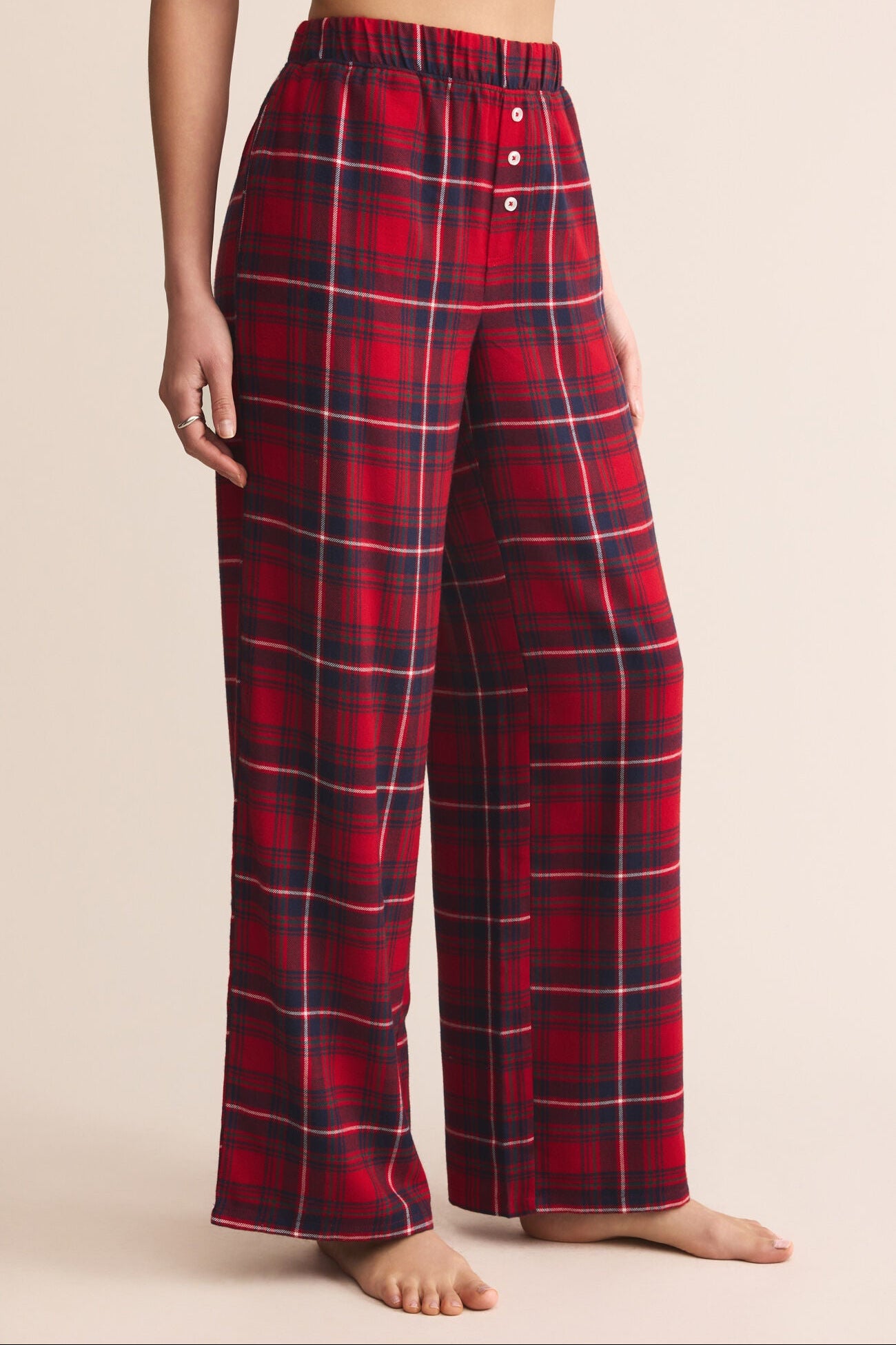 Red plaid pajama pants worn by a person on a beige background