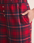 Red and blue plaid pajama pants with a hand in the pocket on a beige background