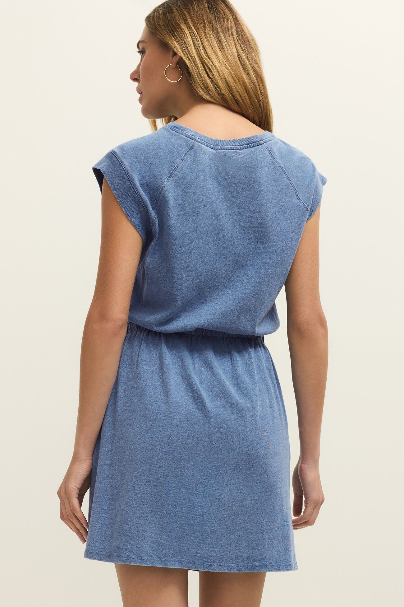 Woman wearing a blue dress against a beige background