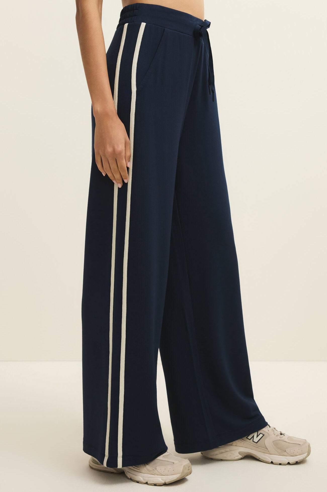 Navy blue wide-leg pants with white stripes on a neutral background