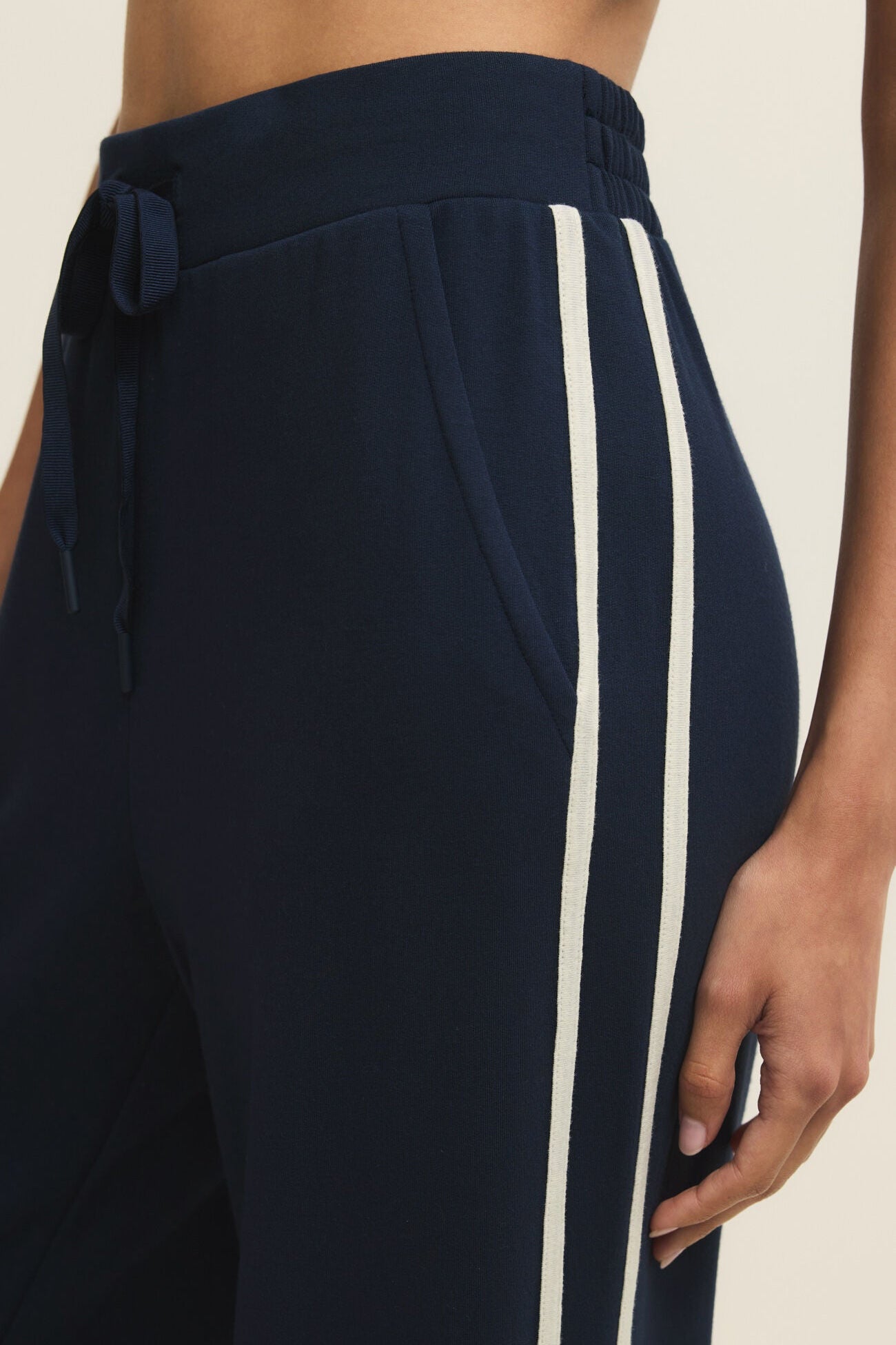 Navy blue pants with a white stripe on a neutral background