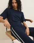 Woman wearing a navy blue outfit with white stripes sitting on a chair.