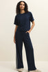 Woman wearing a navy blue outfit with wide-leg pants and a t-shirt on a beige background