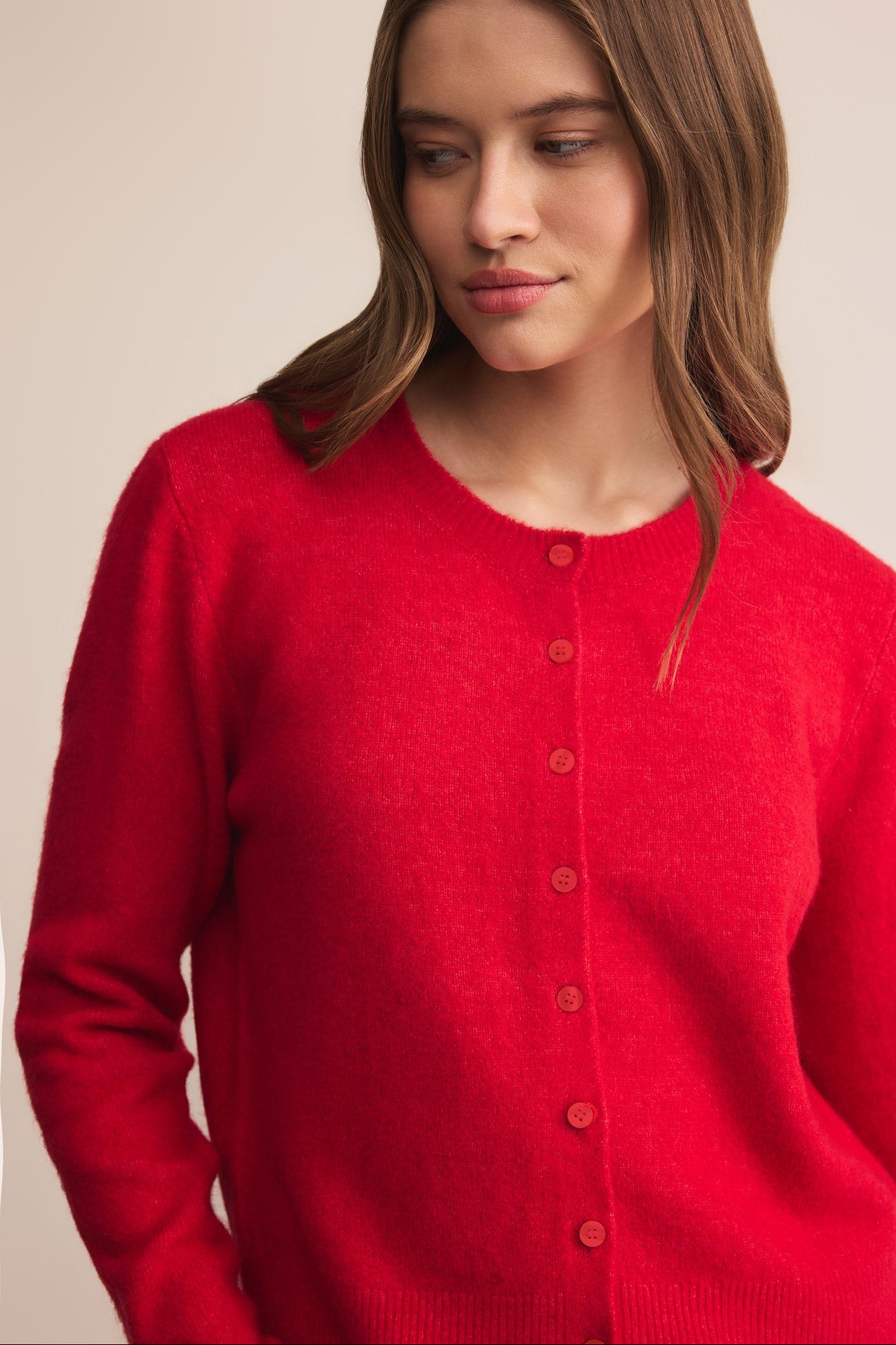 Woman wearing a red cardigan with a beige background