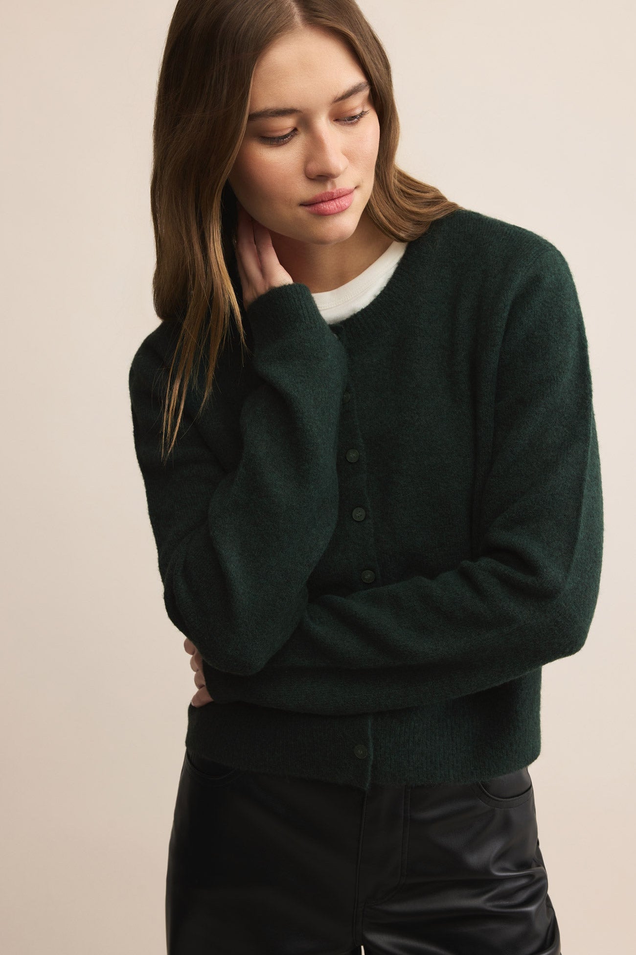 Woman wearing a dark green sweater against a beige background