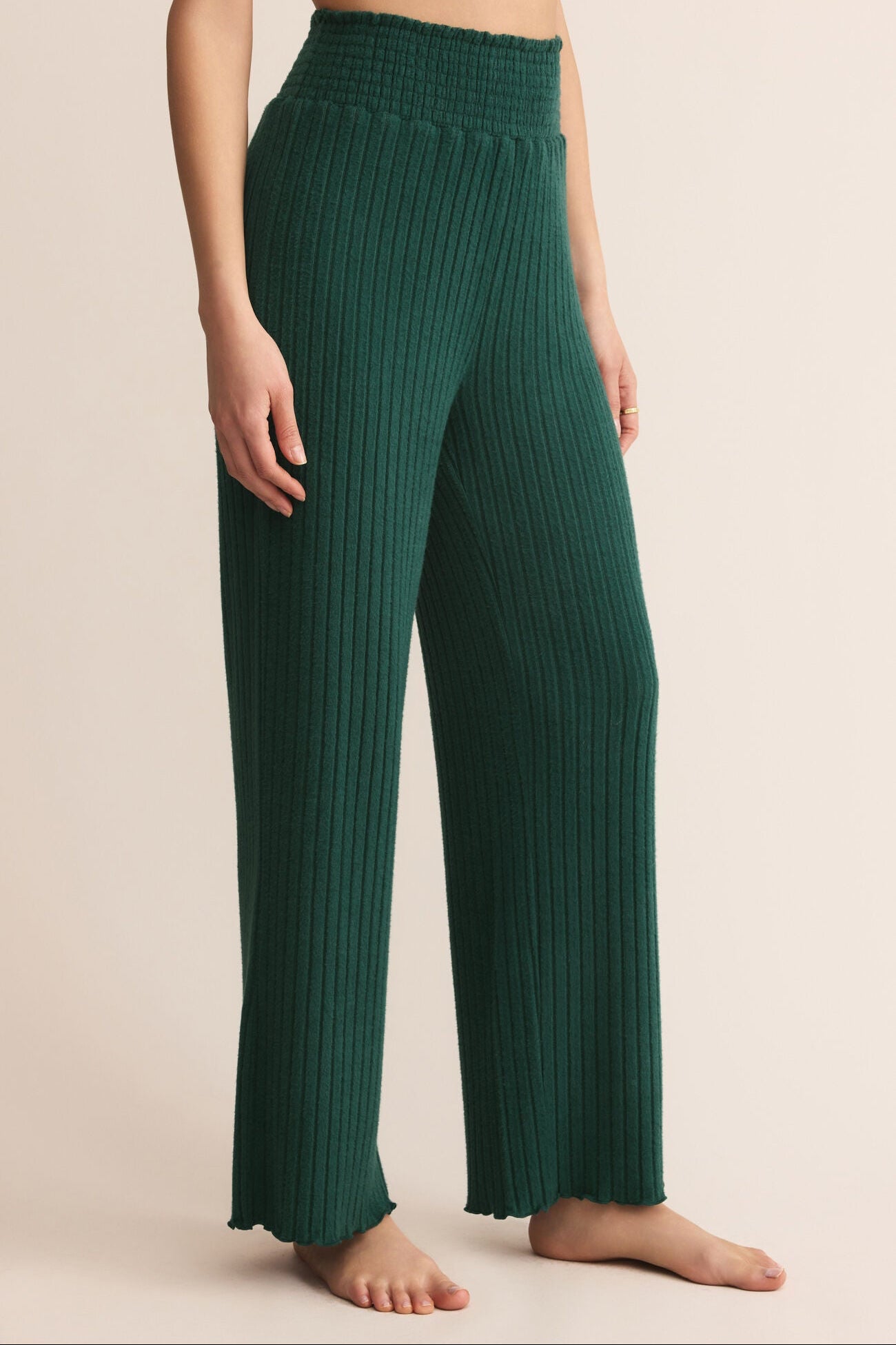 Green ribbed pants worn by a person on a beige background