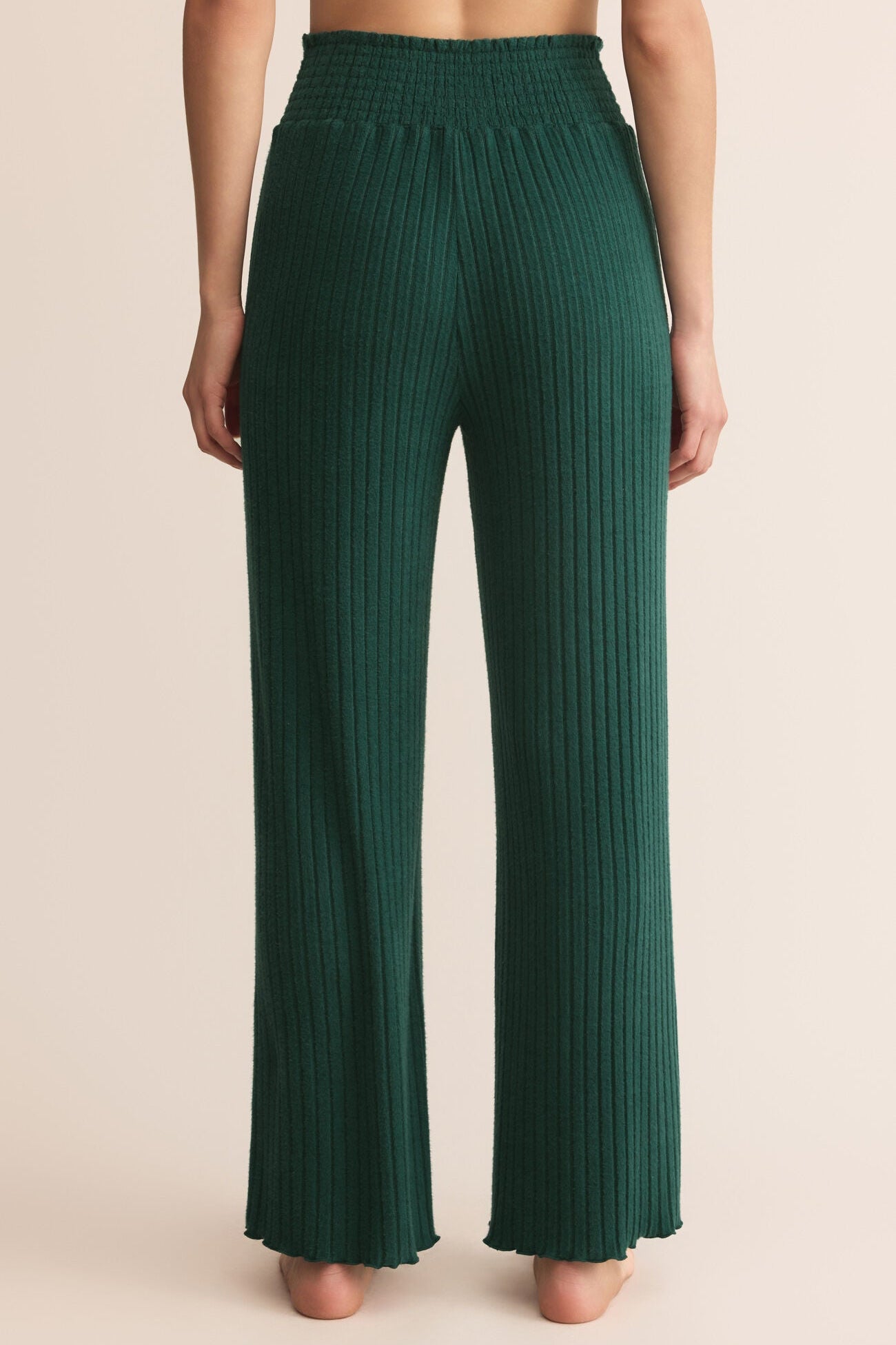 Green pleated pants worn by a person on a beige background
