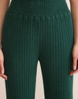 Green ribbed pants worn by a person on a beige background