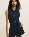 Woman wearing a navy sleeveless shirt dress against a beige background