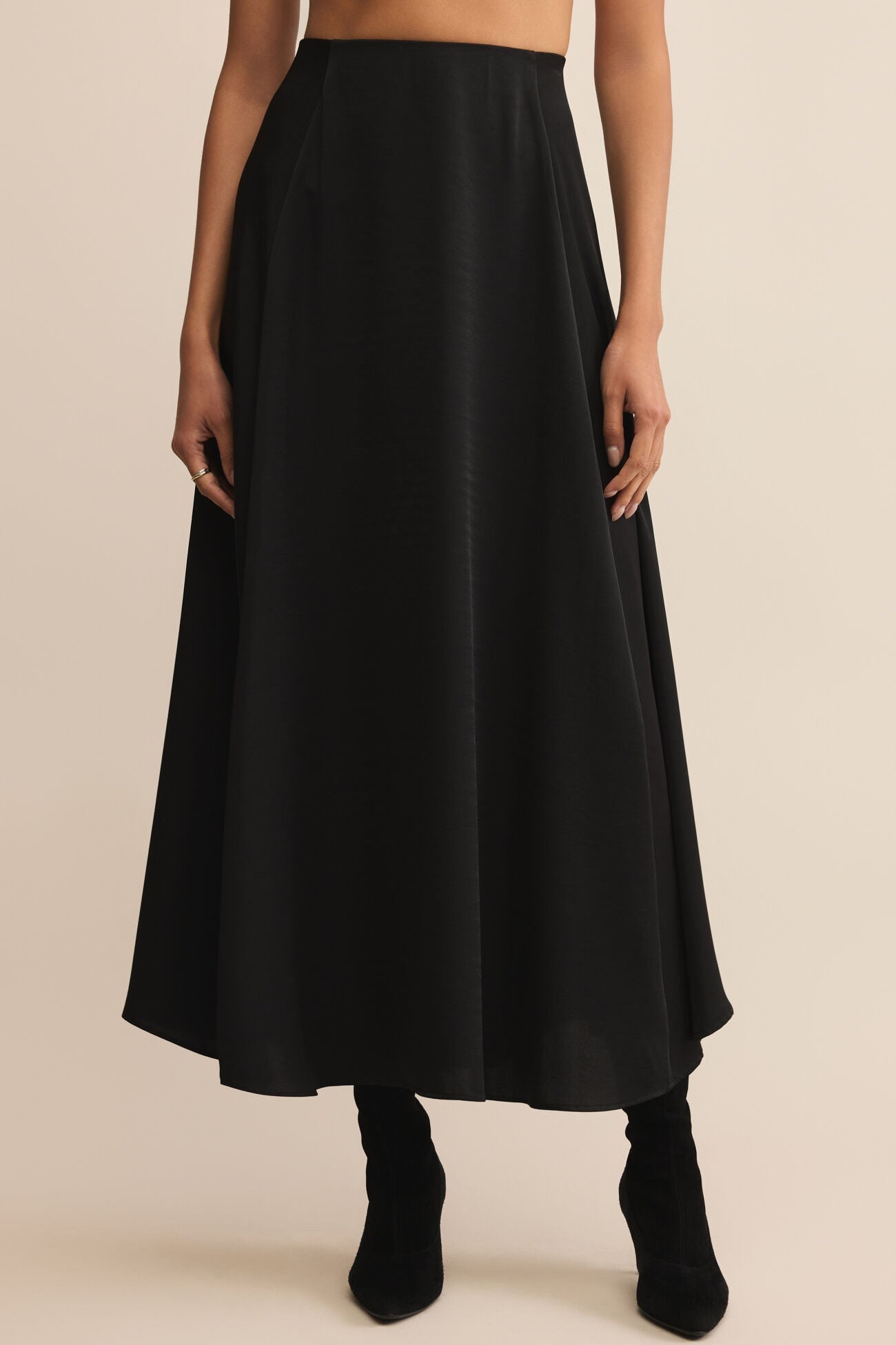 Black skirt worn by a person on a beige background