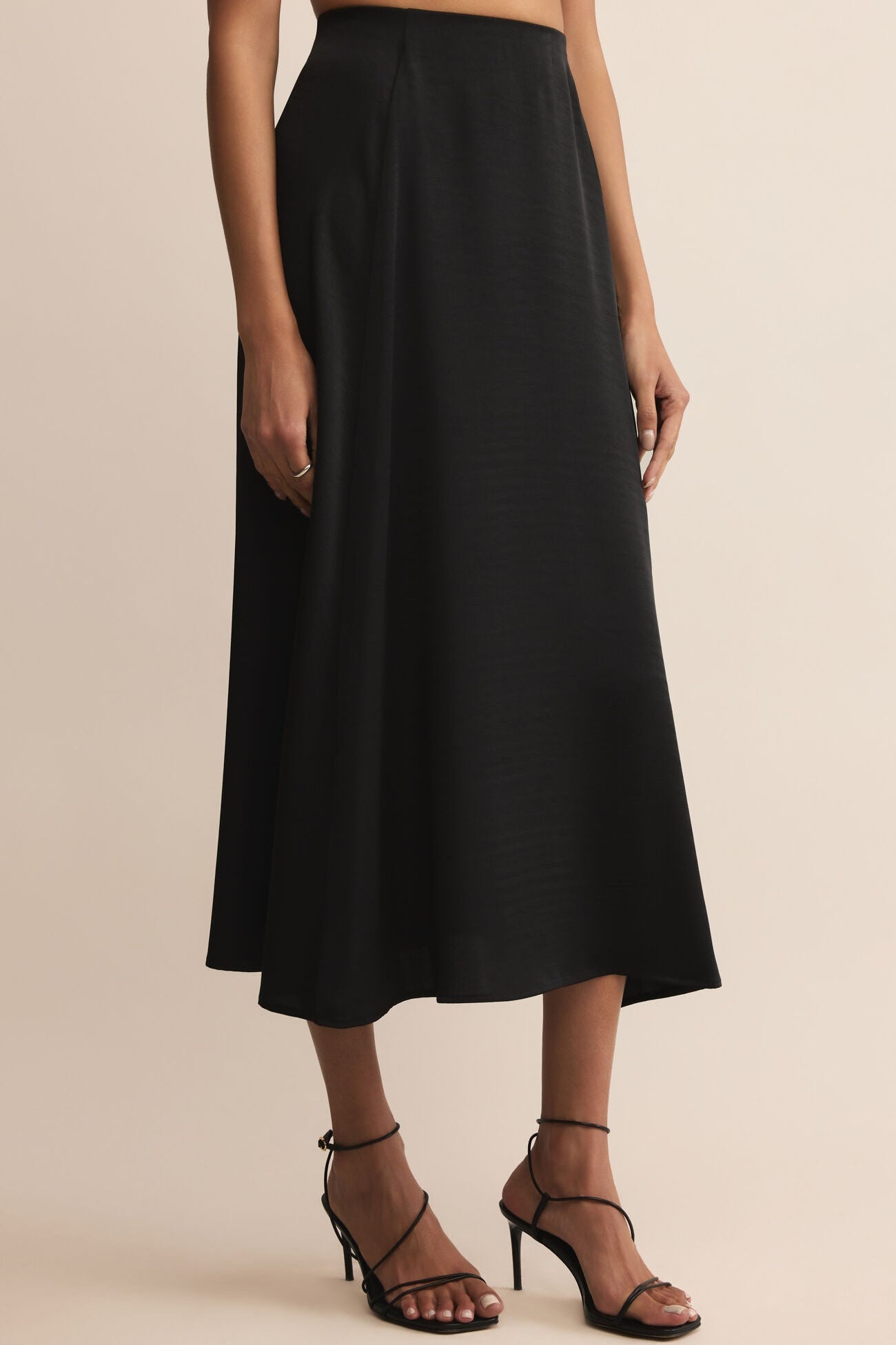Black skirt worn by a person on a beige background