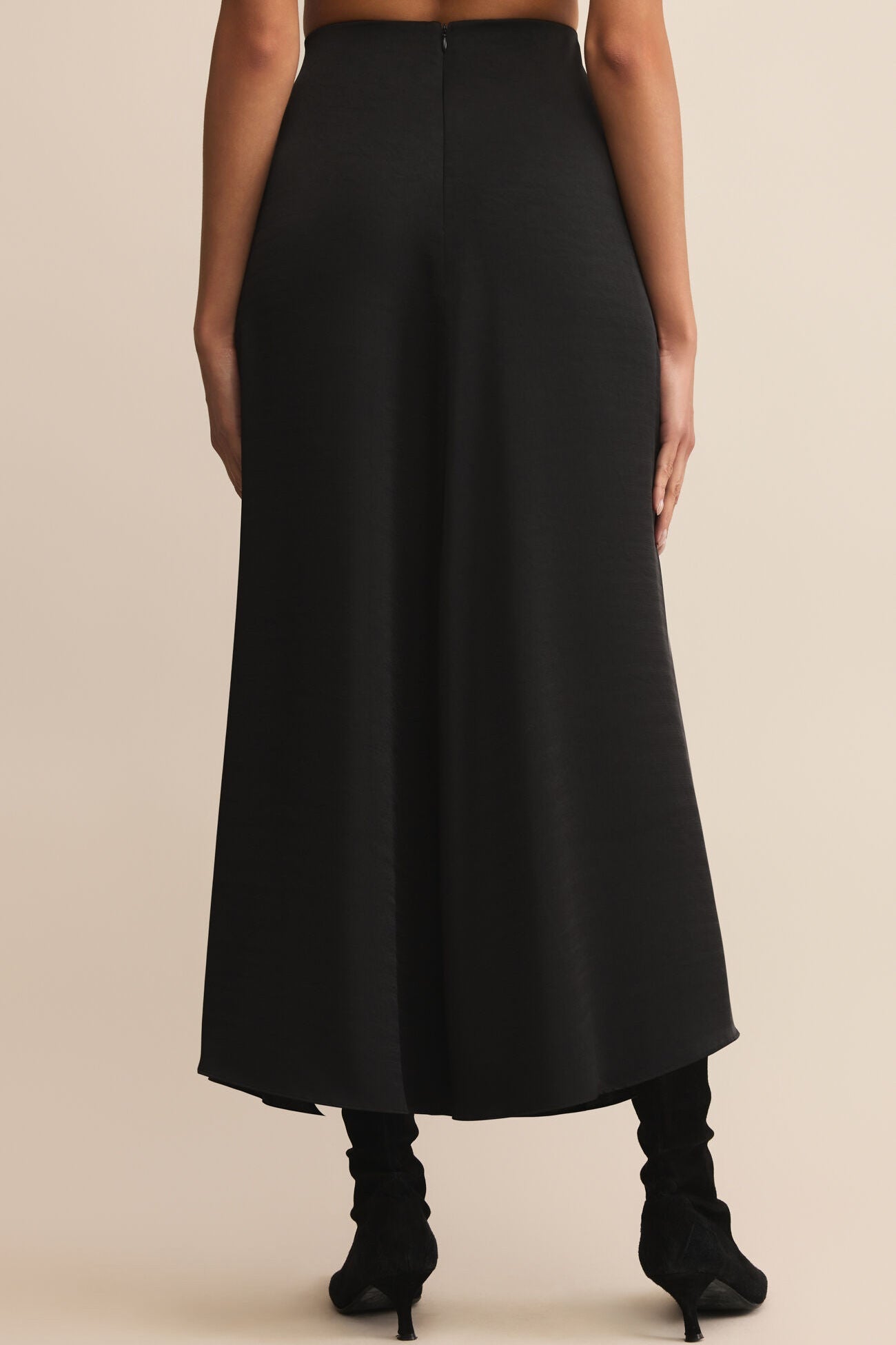 Black skirt worn by a person on a beige background