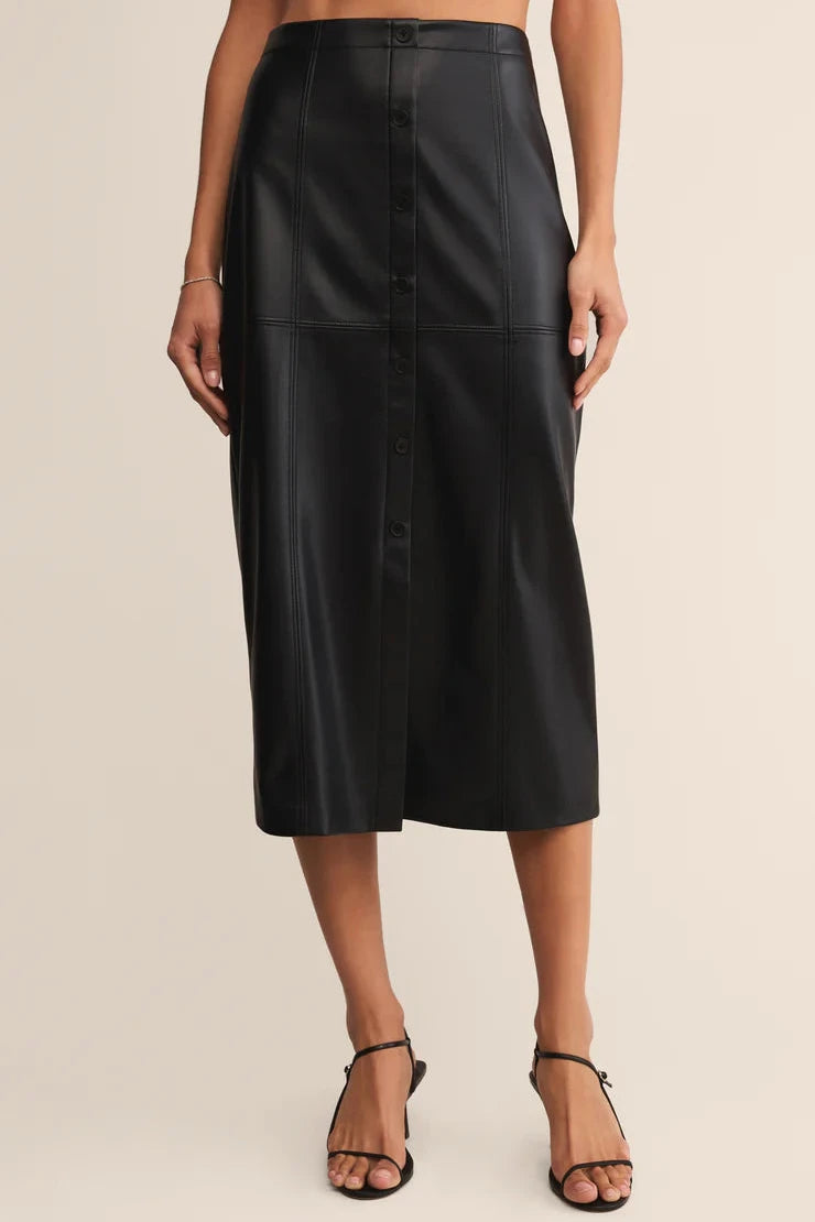 Black leather skirt worn by a person on a beige background